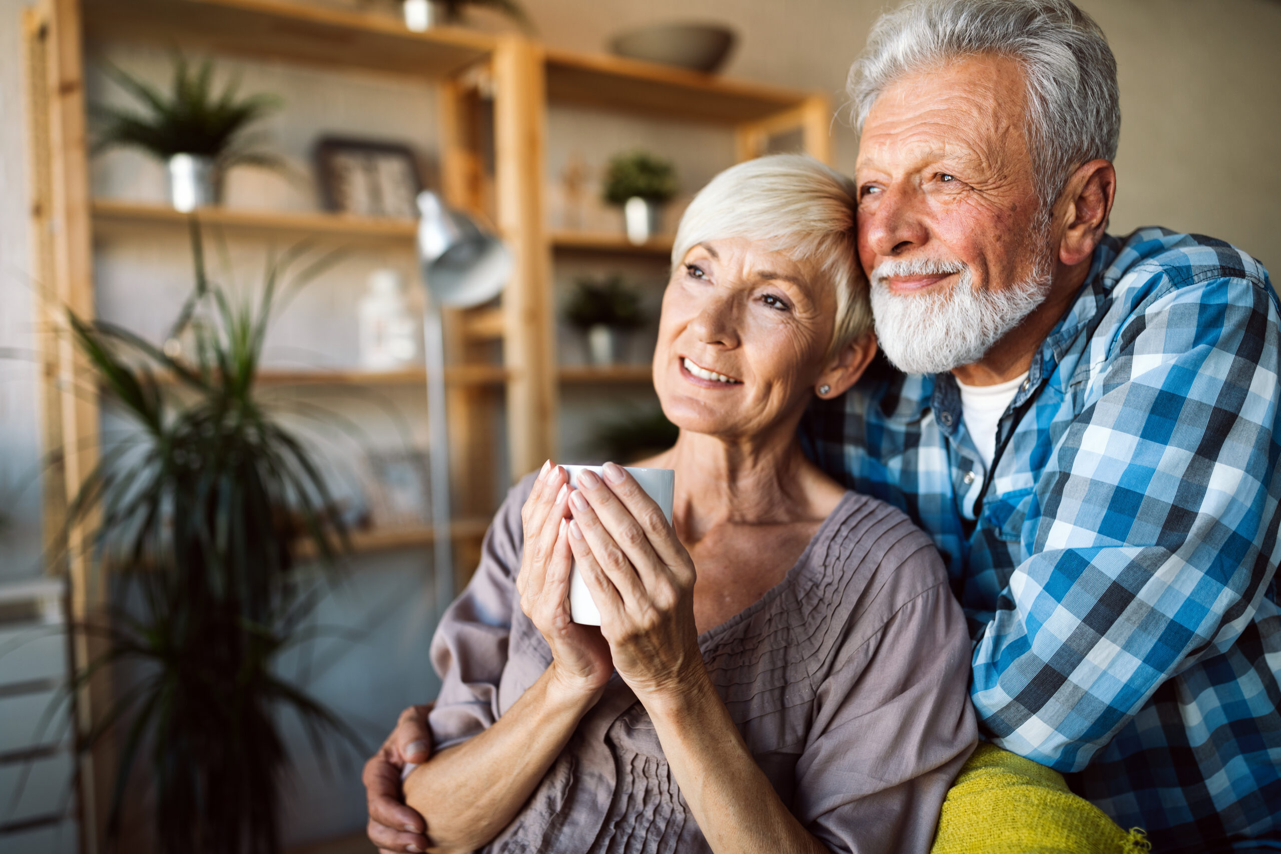 Happy romantic mature couple hugging and enjoying retirement at home