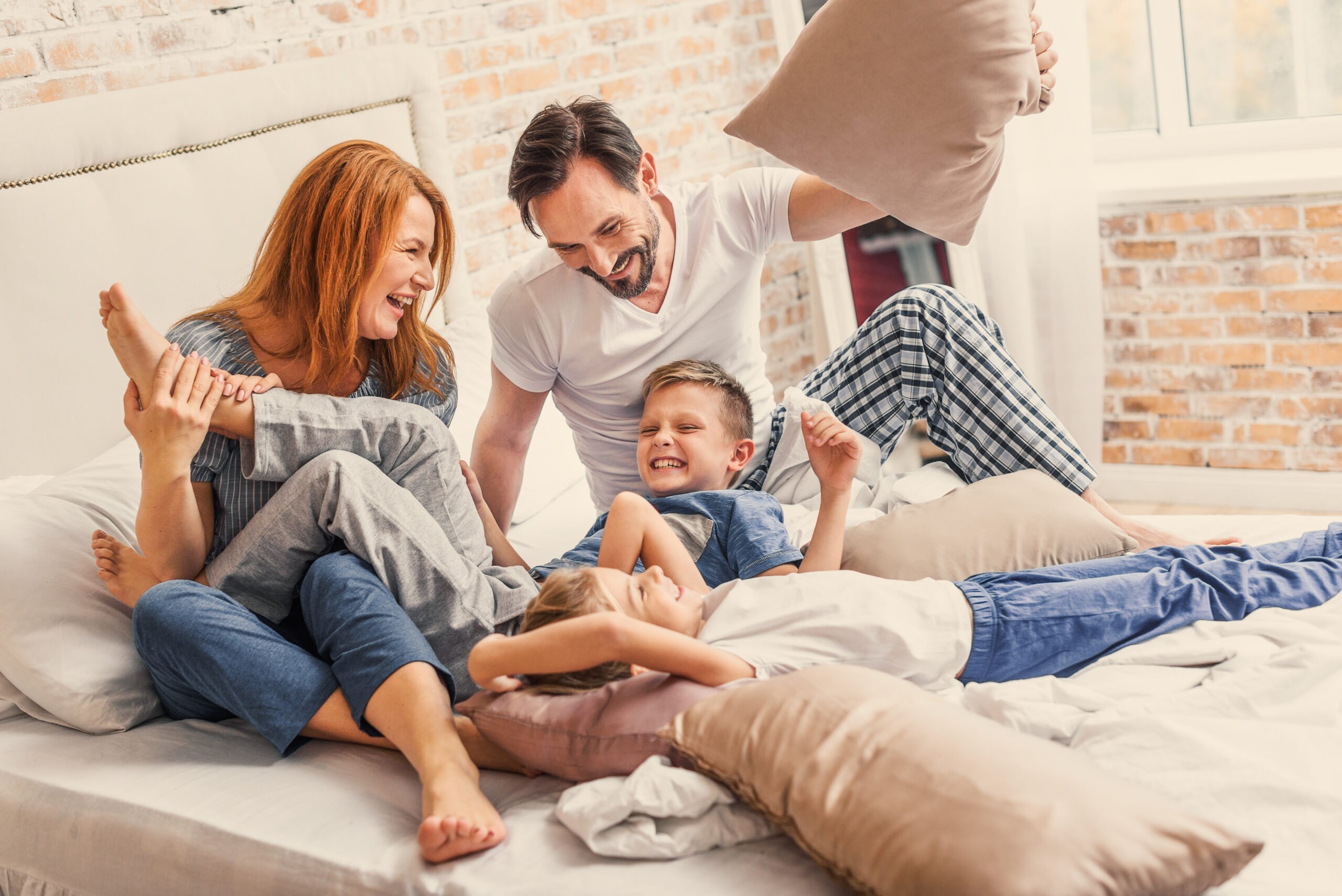 Our happy family. joyful parents spending time with their smiling children while playing with pillows in bed